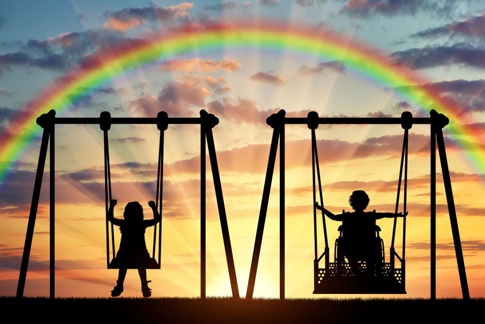 Two children on swings.  One on a wheelchair swing.