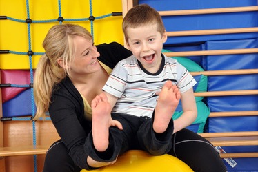 Disabled child with therapist on a physio ball