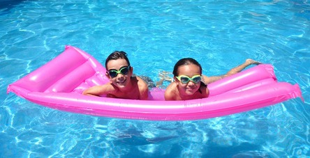 Two girls floating on a pink float in a swimming pool