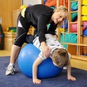 Disabled child with therapist being stretched over a physio ball